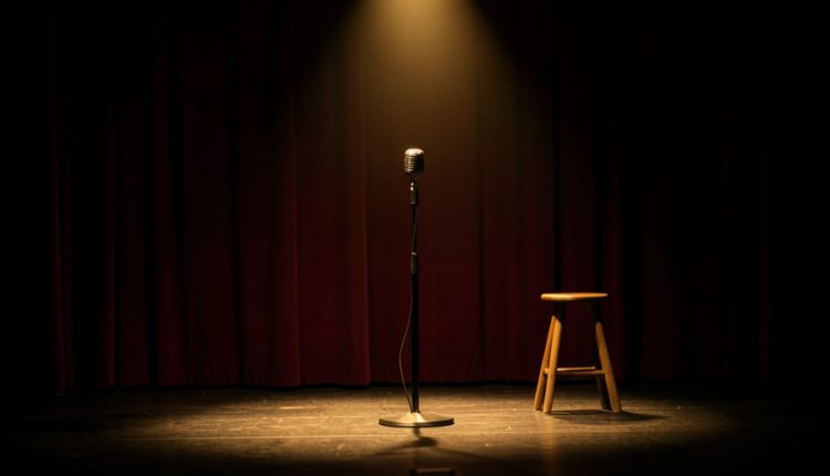 An empty comedy club stage with a vintage microphone on a stand under a warm spotlight, a wooden stool beside it, and a red curtain behind