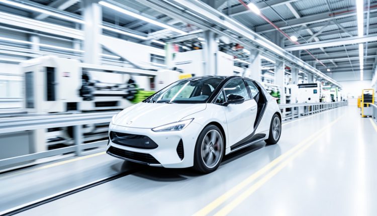 Sleek white car emerging from a bright automotive assembly line with motion blur on the machinery behind it